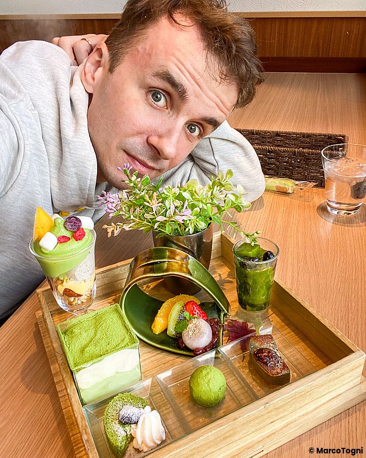 Individuo accanto a un vassoio di dolci giapponesi e tè in una sala da tè a Kyoto.