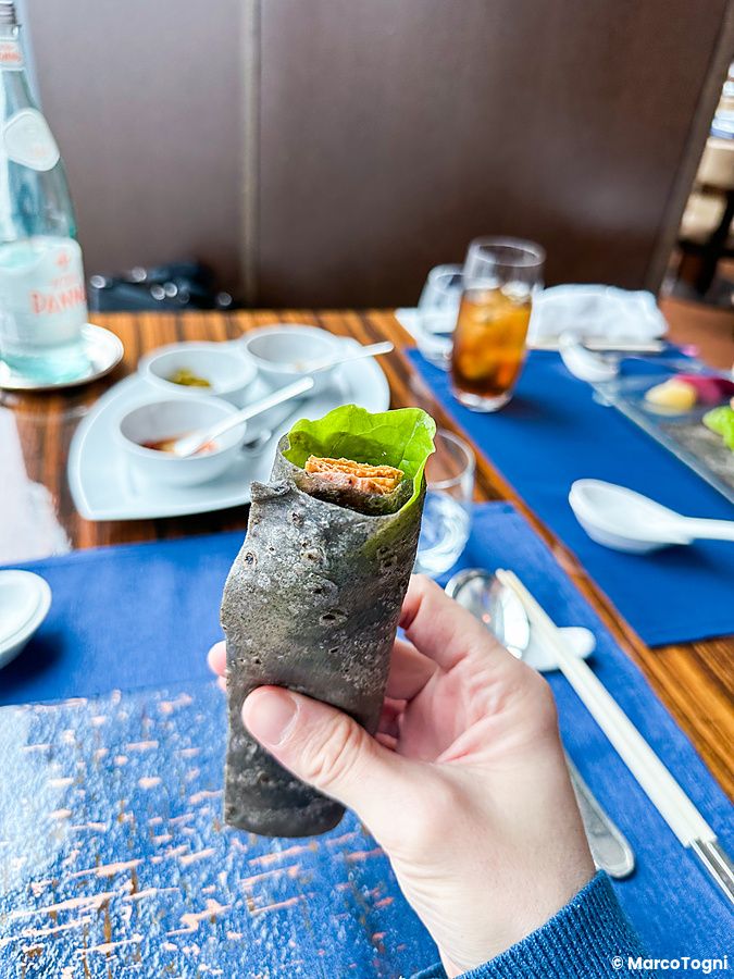 Anatra alla pechinese in crespella nera tenuta in mano al ristorante China Blue nell'hotel Conrad a Tokyo.