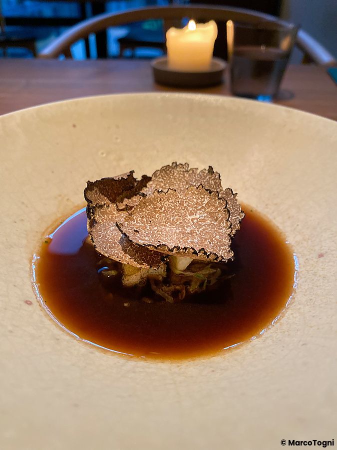 Un piatto di abalone, cavolo e tartufo al Ristorante Crony, Tokyo, servito in una ciotola di ceramica chiara.
