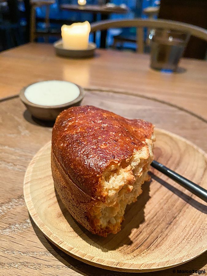 Pane a lievitazione naturale con burro su un piatto di legno al ristorante Crony, Tokyo.