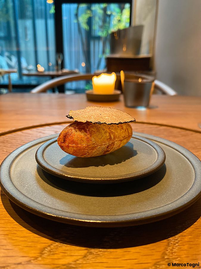 Un soufflé di patata con tartufo nero servito su un piatto di ceramica grigia al Ristorante Crony, Tokyo.
