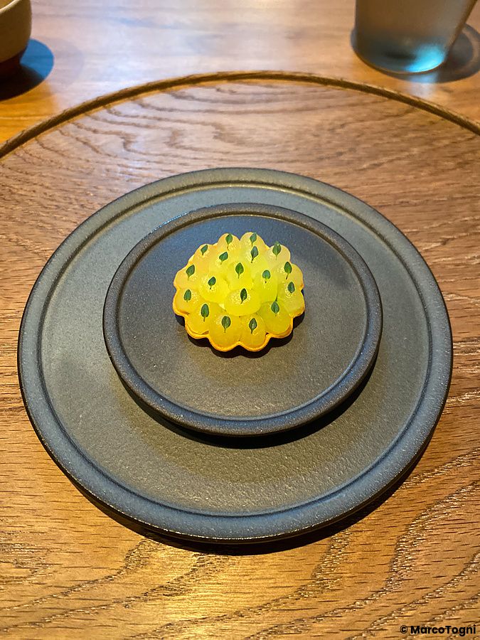 Tartelletta con cetriolo e granchio servita su un piatto di ceramica scura al Ristorante Crony, Tokyo.