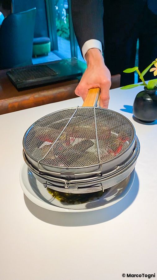 Un uomo serve carboni per scaldare il pesce nodoguro a L'Effervescense, in un ristorante di alta cucina a Tokyo.