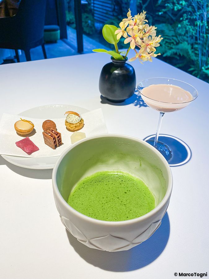 Piccola pasticceria, matcha e succo a base di arachidi serviti su un tavolo presso il ristorante L'Effervescense a Tokyo.