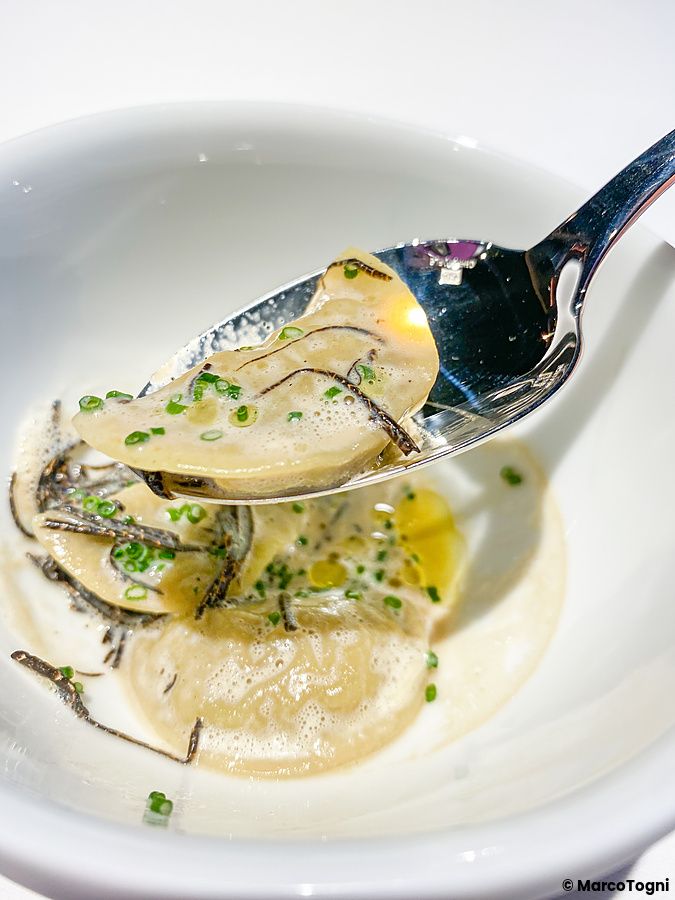 Un cucchiaio solleva ravioli ai carciofi con tartufo nero e pepe giapponese presso il ristorante L'Effervescense a Tokyo.