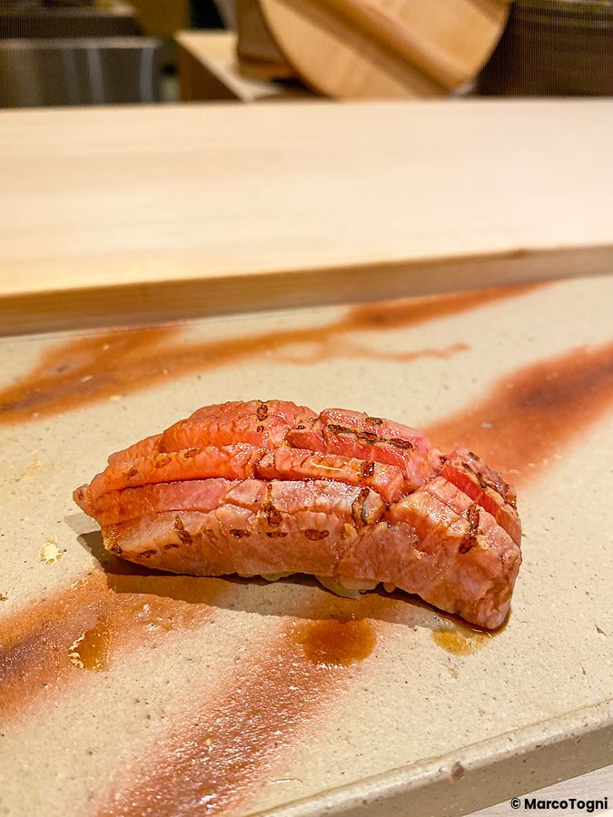 Un nigiri di otoro scottato servito su un piatto di ceramica decorato presso il Sushi Ginza Onodera Souhonten.