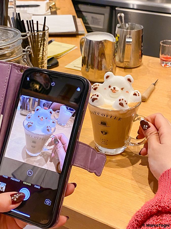 Una persona fotografa con lo smartphone una tazza di cappuccino con latte art a forma di orso presso Hatcoffee ad Asakusa.