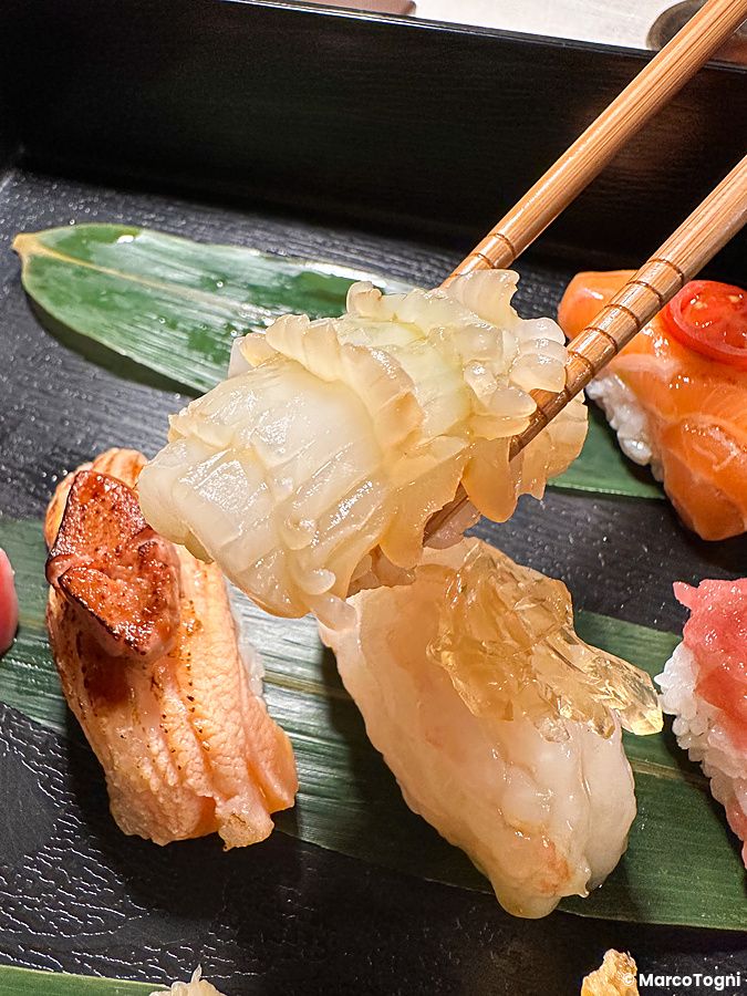 Piatto di sushi assortito con bacchette e foglia verde.