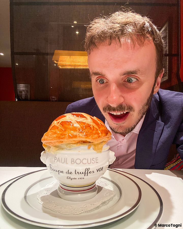 Marco Togni osserva l'iconica zuppa al tartufo di Paul Bocuse servita in una ciotola marchiata a Maison Paul Bocuse.