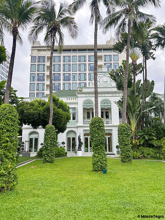 Vista esterna della parte storica al Mandarin Oriental Bangkok con giardini e palme.