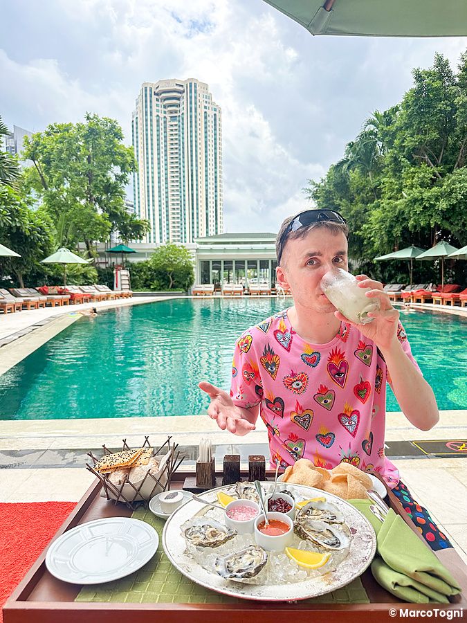Marco Togni che mangia ostriche crude a bordo piscina al Mandarin Oriental Bangkok.