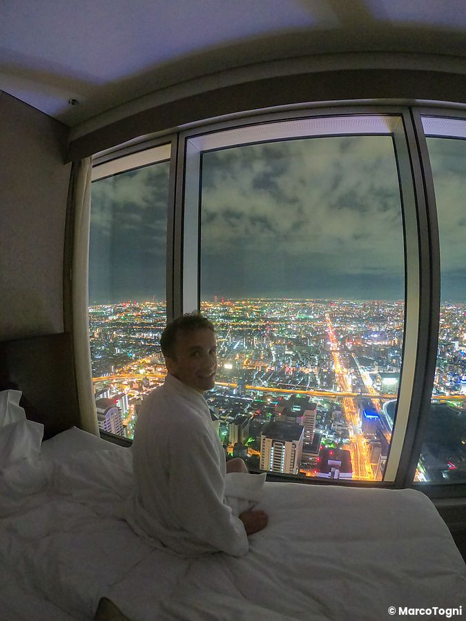 Persona seduta in una camera d'hotel con vista notturna su Osaka.
