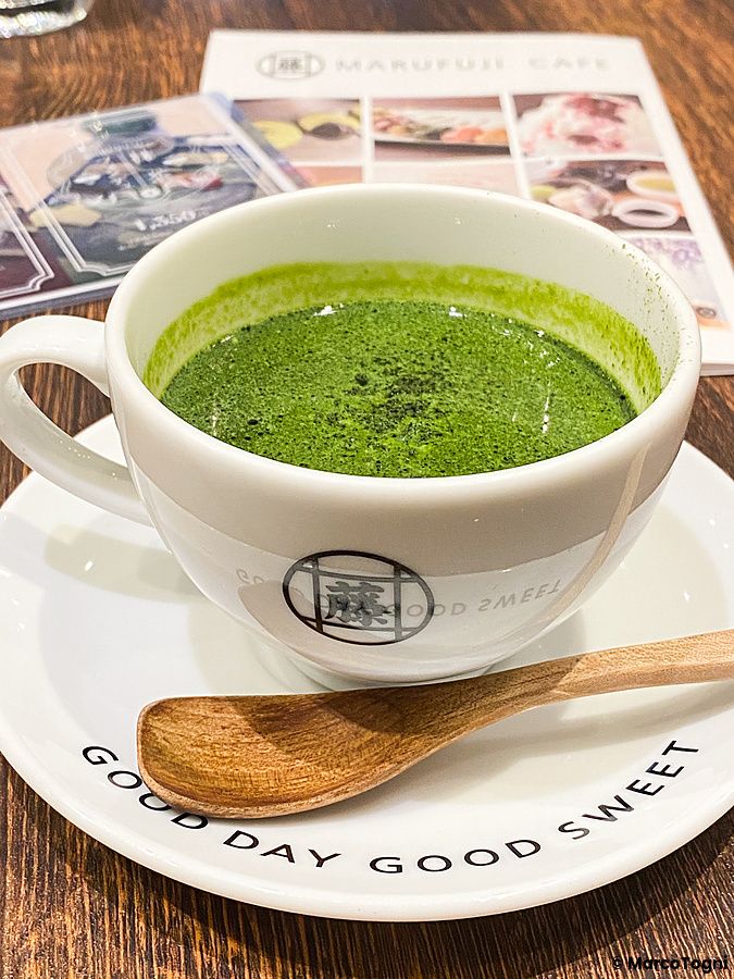 Cappuccino al tè matcha servito in una tazza con logo presso il caffè Marufuji di Osaka.