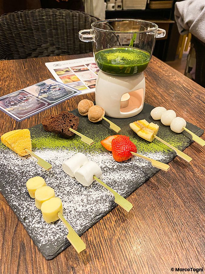 Una fonduta di matcha con spiedini di frutta e dolci servita su un vassoio di ardesia presso il caffè Marufuji.