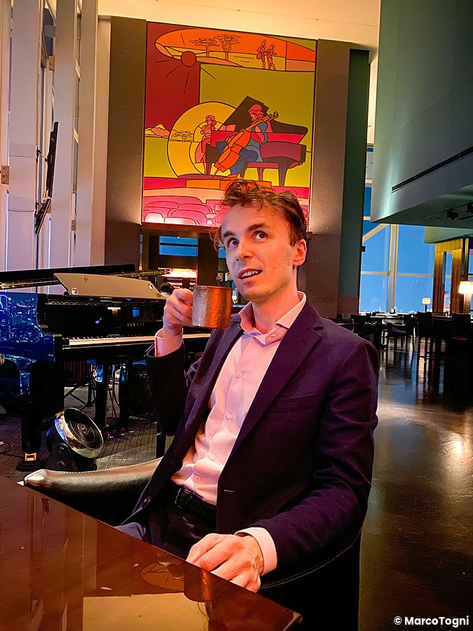 Marco Togni siede all'interno del New York Bar del Park Hyatt Hotel a Tokyo, tenendo in mano una tazza metallica.