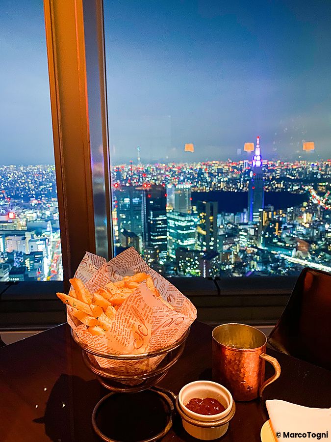 Veduta serale dello skyline di Tokyo dall'interno del New York Bar presso il Park Hyatt Hotel a Shinjuku.