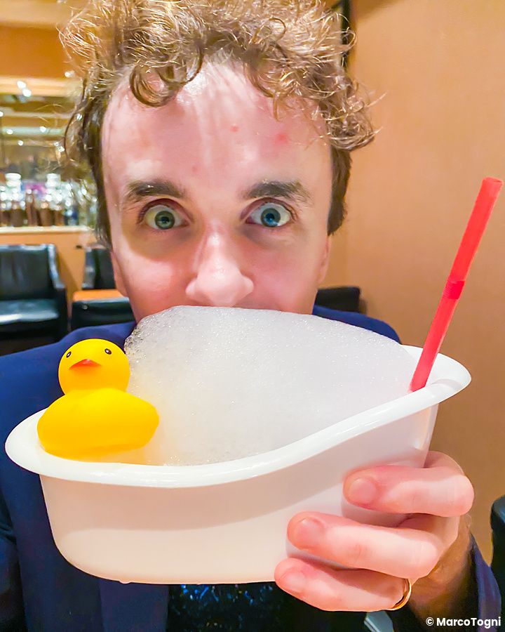 Marco Togni al Orchard Bar di Ginza tiene in mano un cocktail a Orchard Bar servito in una mini vasca con una paperella.