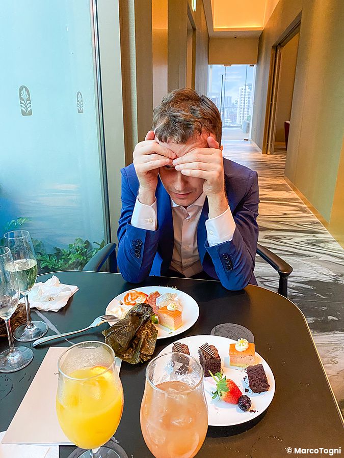 Persona a un tavolo con dolci e bevande nella lounge di un hotel.