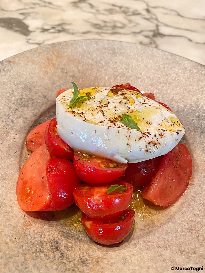 Una burrata con pomodoro servita in un piatto di ceramica presso The Pizza Bar On 38th a Tokyo.