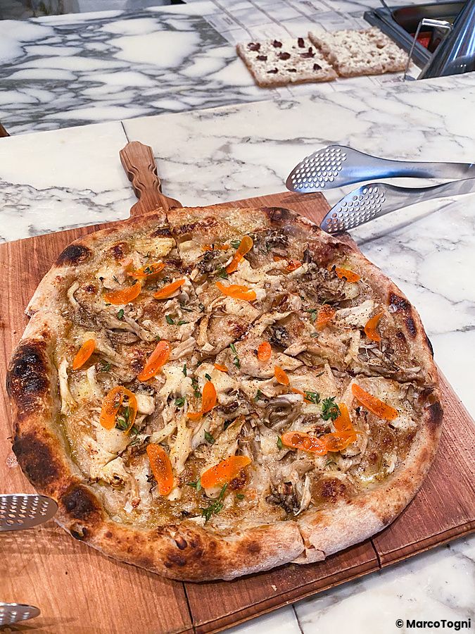Una pizza ai funghi servita su un tagliere di legno presso The Pizza Bar On 38th all'interno del Mandarin Oriental Hotel.