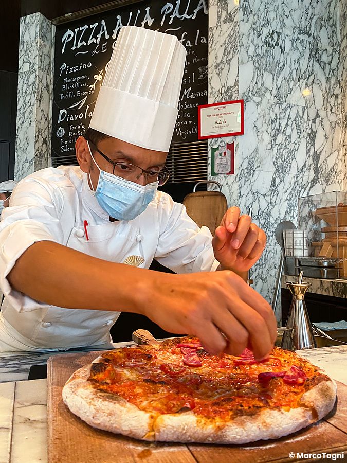 Un pizzaiolo prepara una pizza con salame e rucola al bancone di The Pizza Bar On 38th nel Mandarin Oriental di Tokyo.