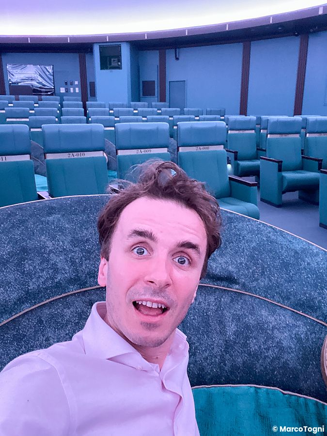 Marco Togni si scatta un selfie all'interno della sala proiezioni del Konica Minolta Planetaria Tokyo con poltrone verdi.