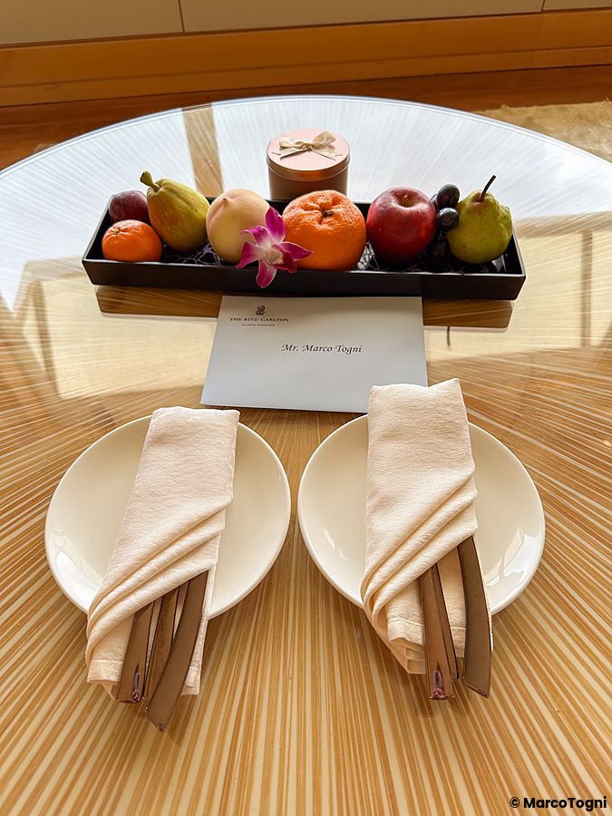 Frutta e messaggio di benvenuto nella suite a The Ritz-Carlton, Millenia Singapore su un tavolo rotondo.
