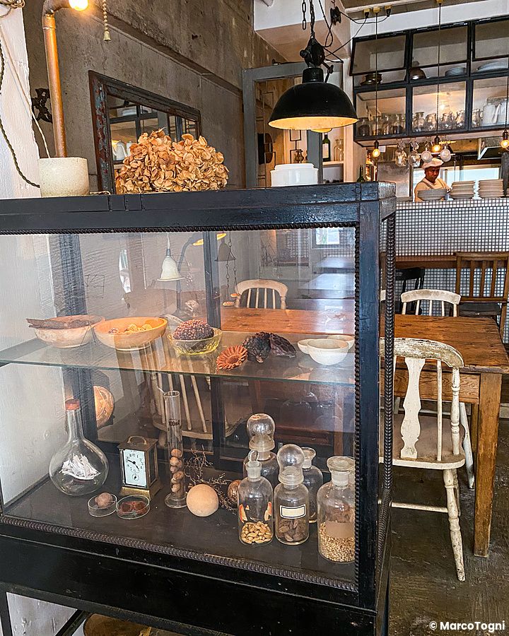 Vetrinetta in legno nero con ampolle e decorazioni all'interno del ristorante Sajilo Clove a Nishi Ogikubo.