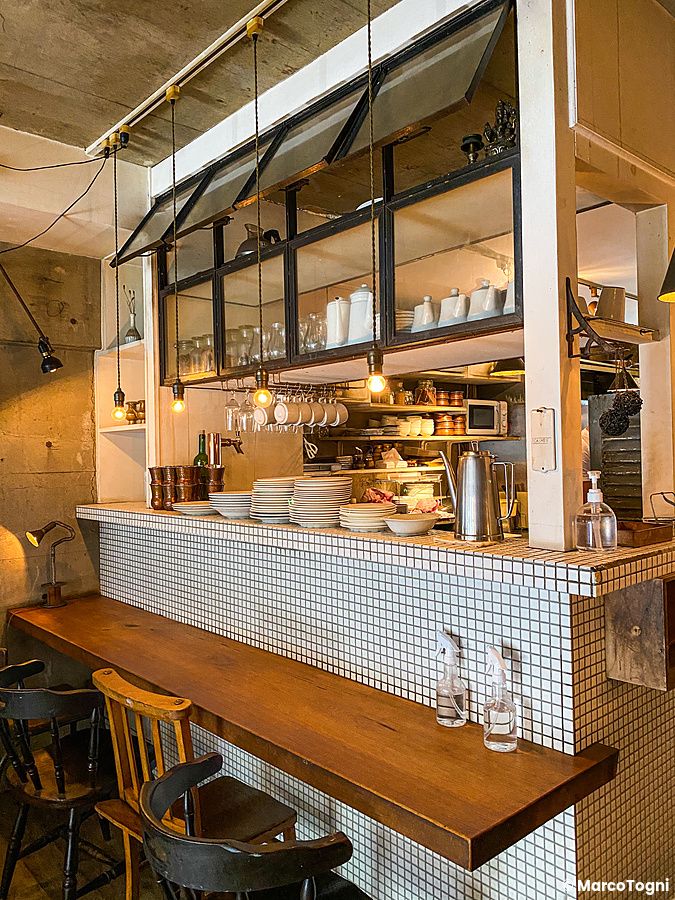 L'interno del ristorante Sajilo Clove a Nishi Ogikubo con bancone piastrellato, sedie in legno e vista sulla cucina.