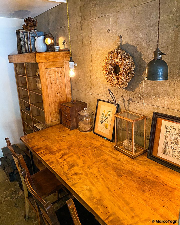 Interno del ristorante indiano Sajilo Clove a Nishi Ogikubo, con tavolo in legno e decorazioni alle pareti in cemento.