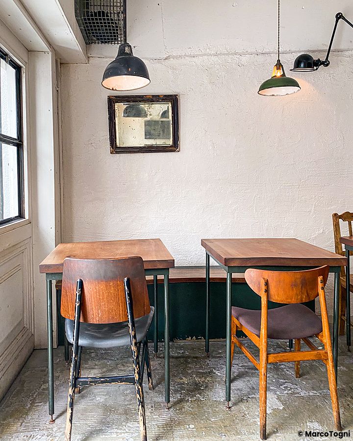 Interno del ristorante Sajilo Clove a Nishi Ogikubo con tavoli in legno e sedie vintage contro una parete chiara.
