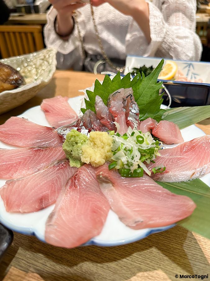 Un piatto di sashimi con fette di pesce, wasabi e zenzero servito presso il ristorante Sushi no Darihan a Shinjuku.