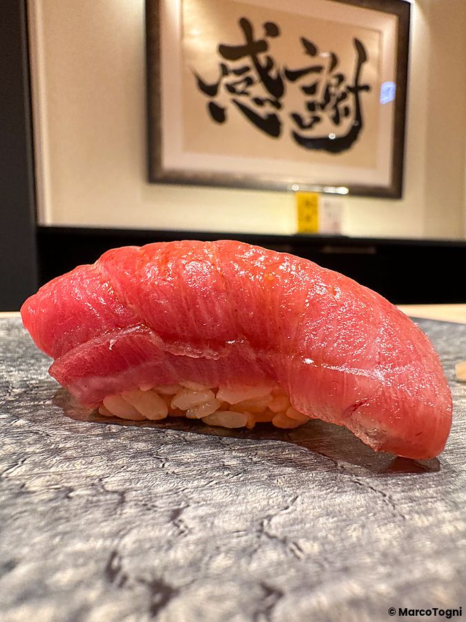 Un nigiri di chutoro è servito su un piatto di pietra scura all'interno di da Sushi Punch a Tokyo.