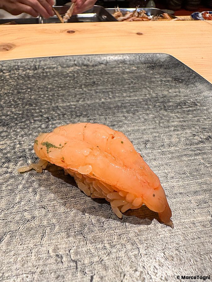Un nigiri di gambero crudo servito su un piatto di pietra scura all'interno del ristorante Sushi Punch a Tokyo.