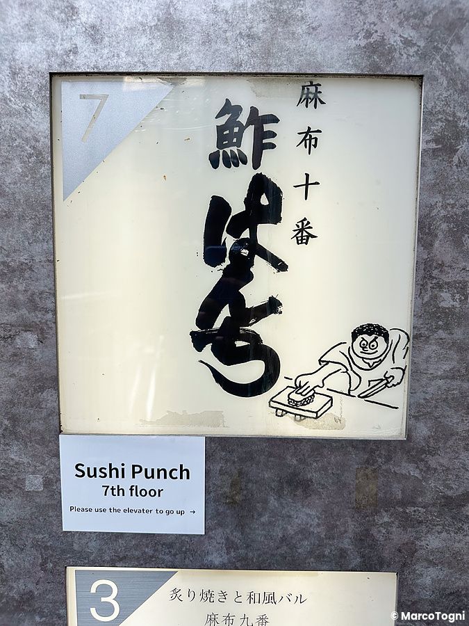 L'insegna all'ingresso a Sushi Punch con scritte in giapponese, un disegno stilizzato e l'indicazione del settimo piano.