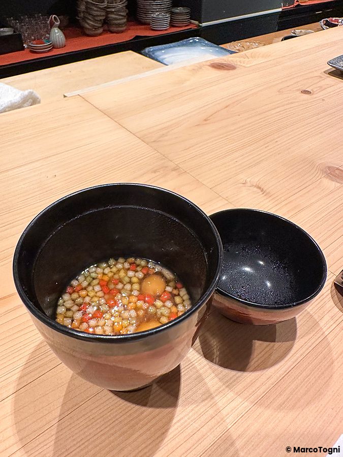 Una ciotola di zuppa a Sushi Punch su un bancone di legno chiaro in un ristorante di Tokyo.