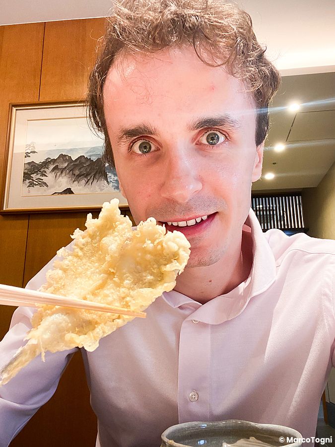 Marco Togni tiene tra le bacchette un pesce a Tempura Kondo presso il ristorante Tempura Kondo a Ginza.