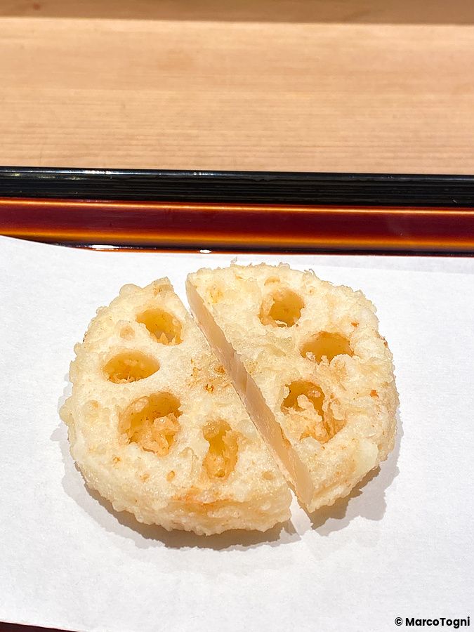 Una radice di loto a Tempura Kondo tagliata e fritta in pastella, servita su carta bianca in un ristorante di Ginza.