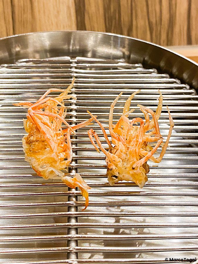 Due teste di gambero fritto sono appoggiate su una griglia metallica al ristorante Tempura Shimomura a Tokyo.