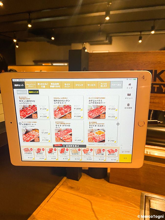 Tablet per ordinare a Yakiniku Like montato su un tavolo in legno all'interno del ristorante giapponese.