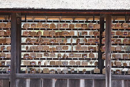 Una parete di legno a Hiroshima decorata con numerose tavolette votive (ema) legate con cordini bianchi.