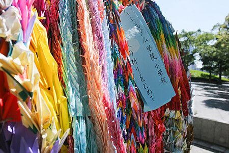 Molteplici gru di carta piegate di vari colori appese in un luogo commemorativo a Hiroshima.