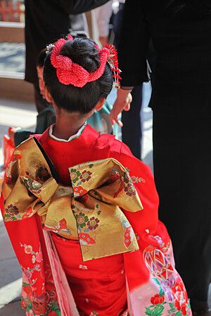Bambina in kimono rosso con fiocco dorato al santuario Tsurugaoka Hachiman.