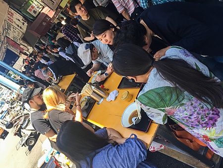 persone sedute a tavoli all'aperto presso il ristorante Kitsuneya a Tsukiji.