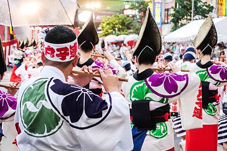 Persone in abiti tradizionali suonano flauti durante la parata del Koenji Awa Odori a Tokyo.