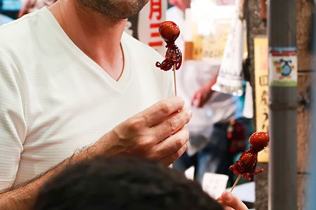 Persona con spiedino di polpo al mercato Nishiki a Kyoto.