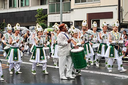 Persone in costumi colorati suonano strumenti a percussione al carnevale Asakusa Samba a Tokyo.
