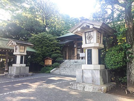Due lanterne in pietra fiancheggiano il vialetto d'accesso verso una struttura in legno del Santuario Togo a Tokyo.