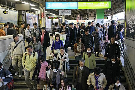 Una folla di persone scende le scale in una stazione giapponese