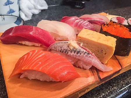 Un assortimento di nigiri e gunkan sushi servito su un tagliere di legno al ristorante Sushidokoro Okame a Tokyo.
